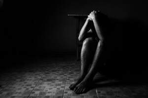 Person sitting on the floor with hands on their head feeling guilty