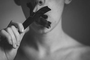 Teen with duck tape over his mouth symbolizing a wounded voice